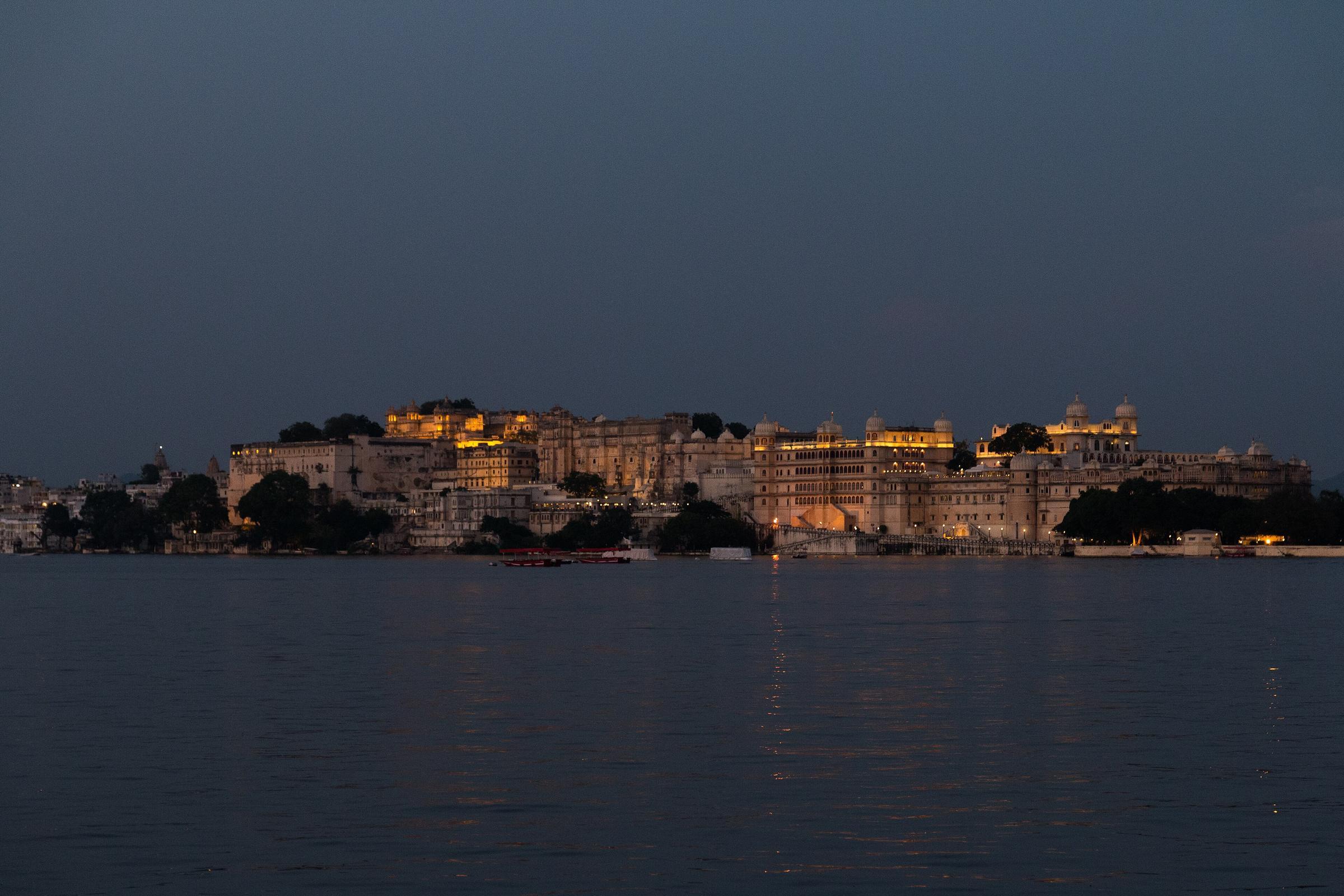 The City Palace lit up at dusk, seen across Lake Pichola from the island of Jag Mandir.