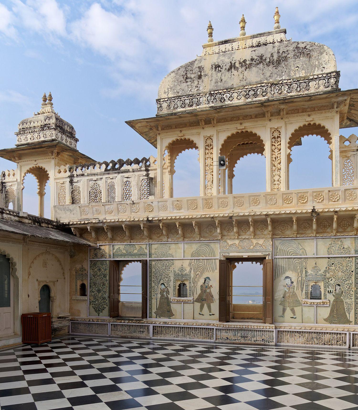 A courtyard of the City Palace with a pavilion of scalloped arches above a black-and-white tiled floor.