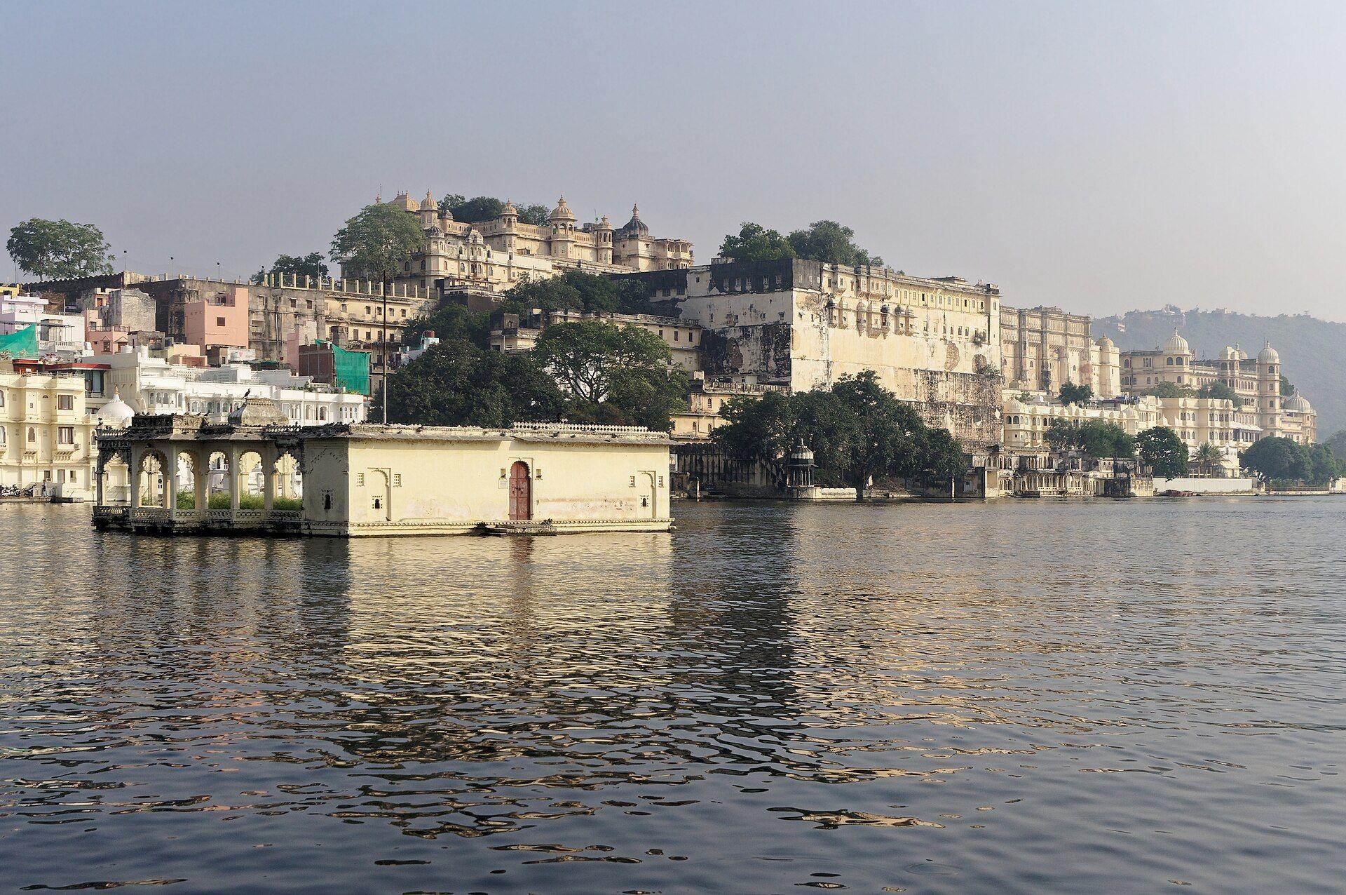 The City Palace stepping up its hill beside Lake Pichola, with a pavilion standing in the water in front.