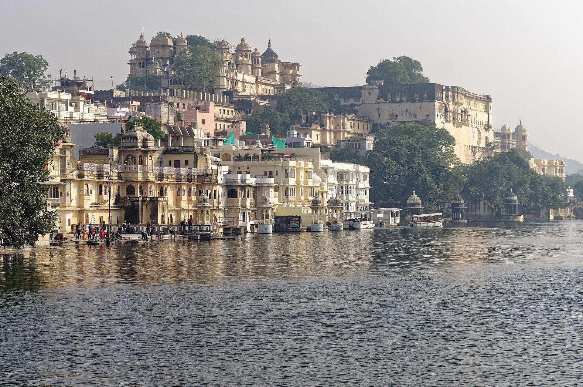 Ghats and old houses on the shore of Lake Pichola, with the City Palace rising behind them.